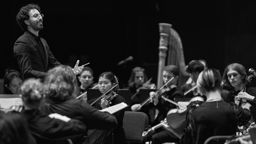 A conductor conducts the summer orchestra, photo by Darrell Owens