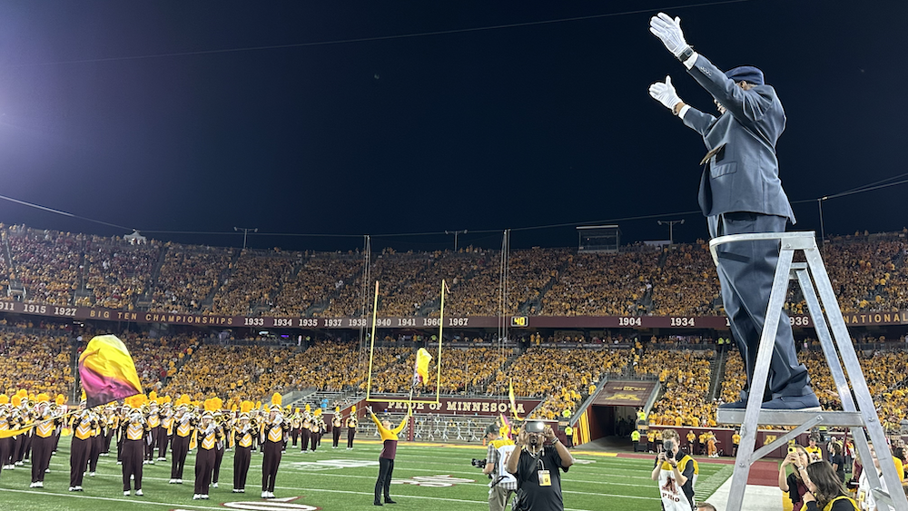 O'Neill Sanford conducts in front of the present-day Minnesota Marching Band at the halftime ceremony. 