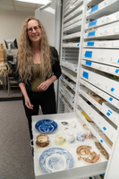 Kat Hayes stands before a drawer of artifacts