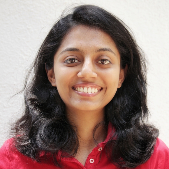A photo of Rucha Markale, smiling and wearing a red shirt with a white background