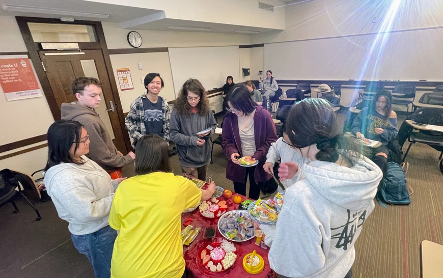 Students gather around a table of authentic Chinese snacks