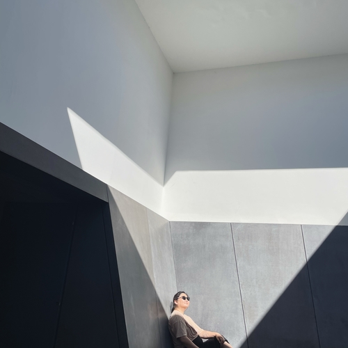 A woman lounges in a James Turrell aperture illuminated by a triangle of light.