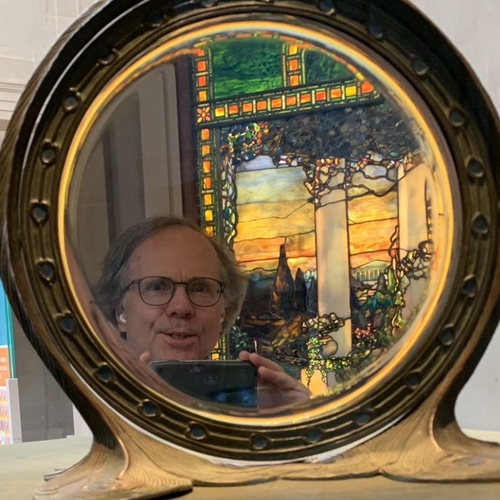 Man taking photo of himself in round mirror with ornate frame