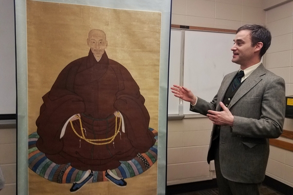 Prof. Greenberg next to an artwork in a classroom
