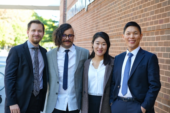 Group of four graduate students smiling, three men and one woman