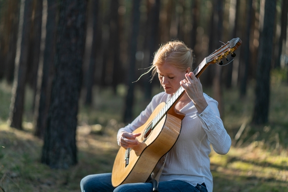 Eva Beneke holds her guitar in an outdoors setting