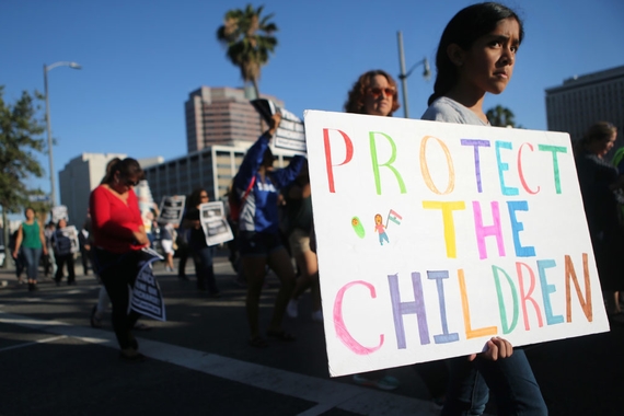 A young girl marching with a sign that says "PROTECT THE CHILDREN"