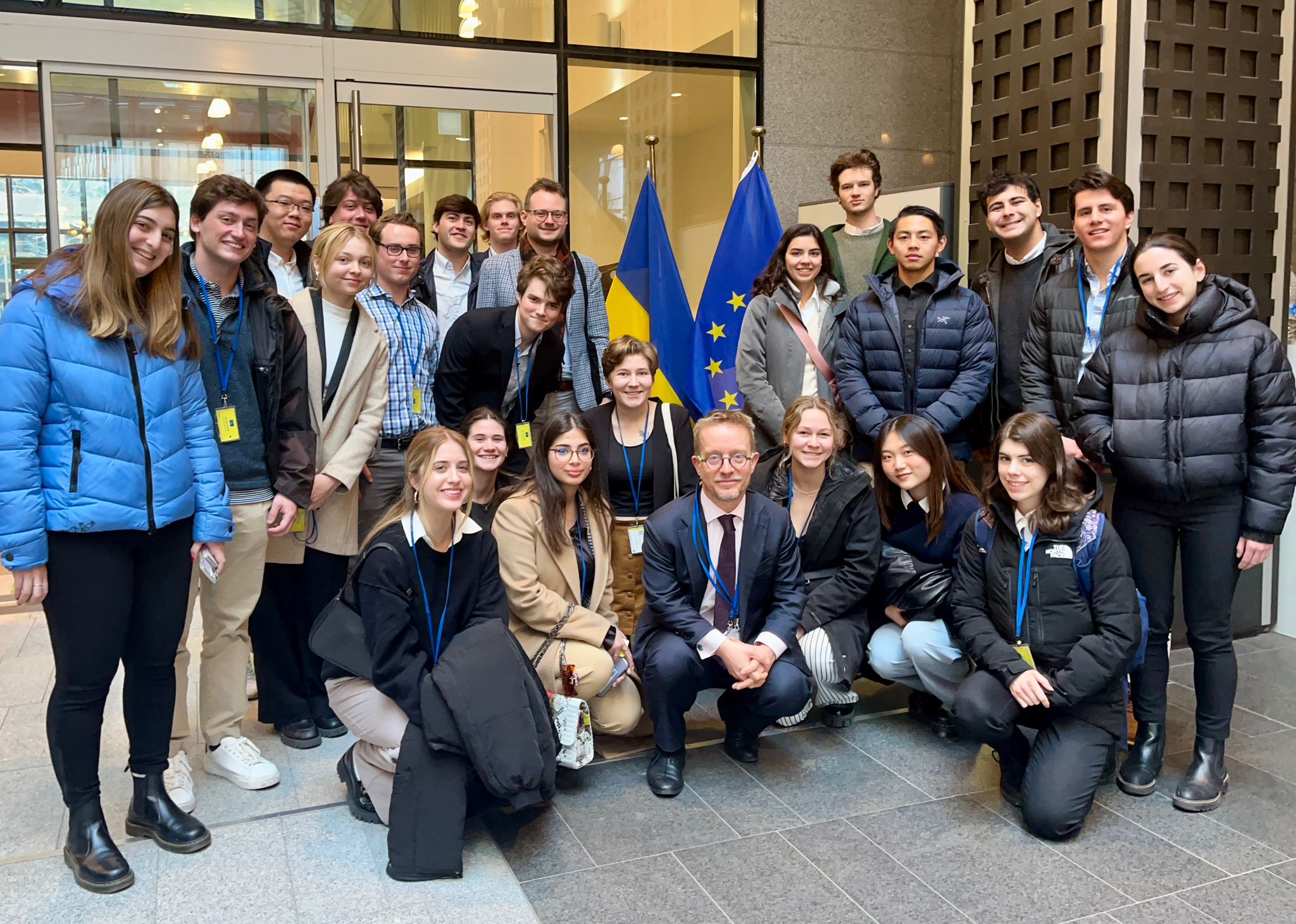 Group of students standing and kneeling. EEAS and Ukraine flag behind group.