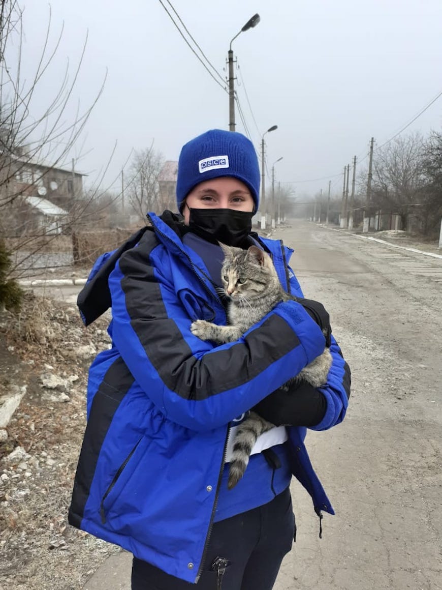 woman in matching hat and jacket wearing a face mask and holding a cat