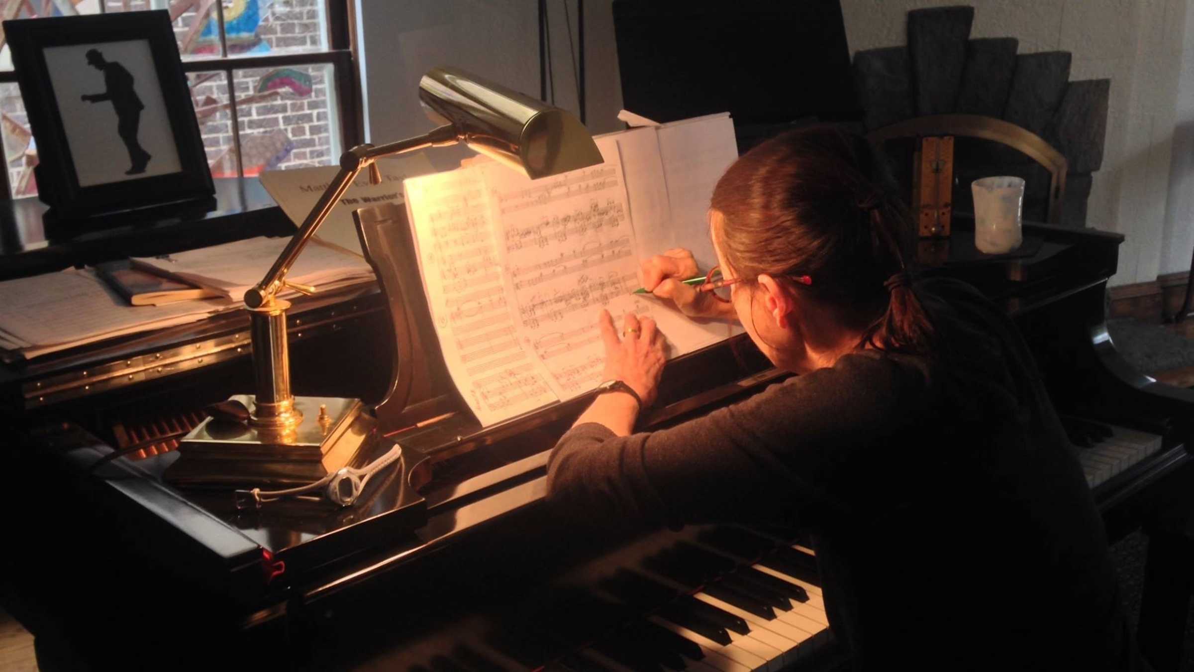 Libby Larsen works on a piece of music over a piano. 