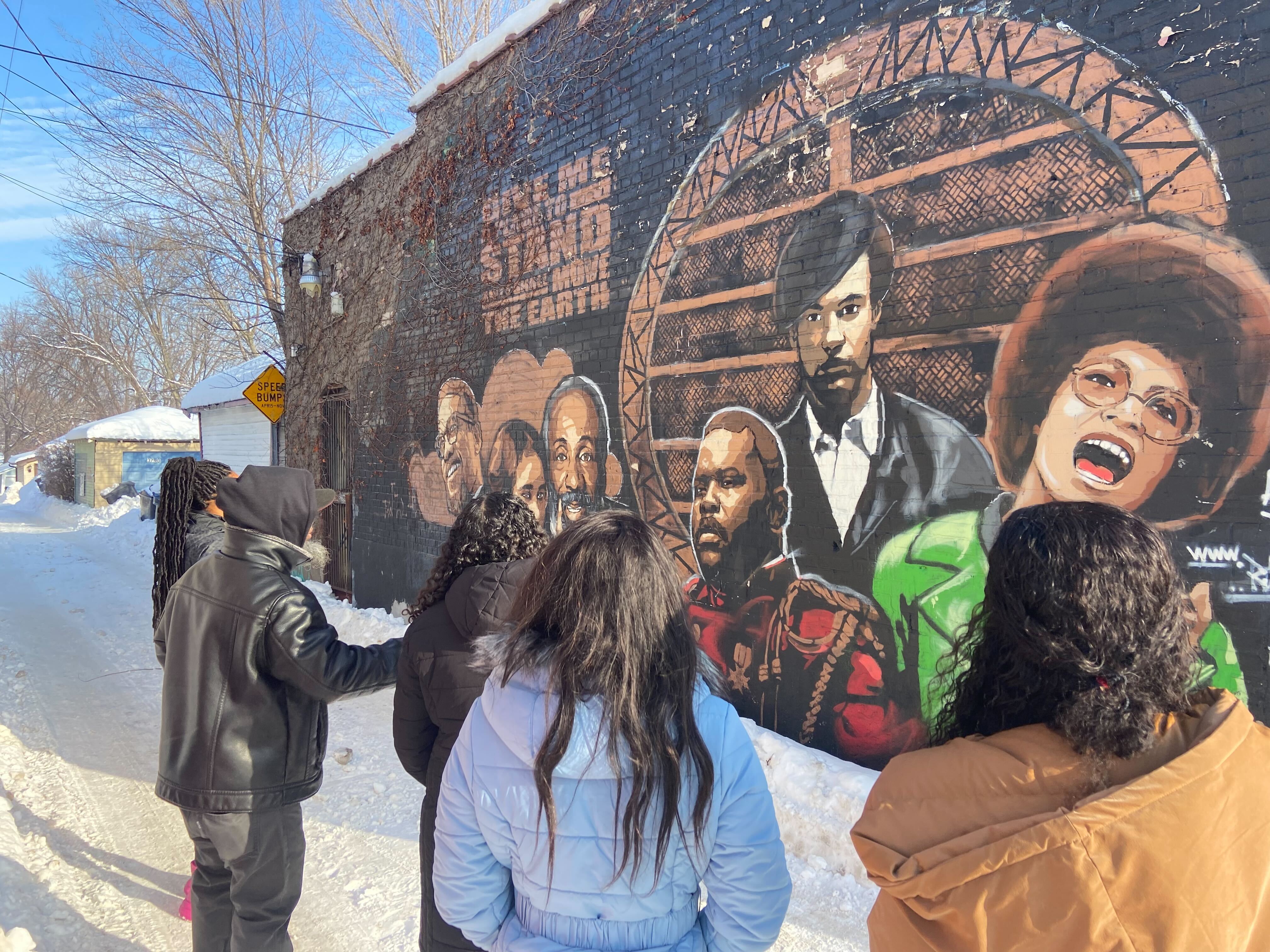 CLA students stand in front of mural of Black leaders.