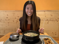 photo of woman with brown hair eating ramen with chopsticks