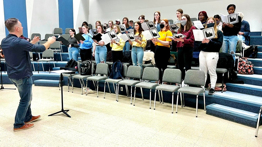 A choir is being led in rehearsals by Matthew Mehaffey. 