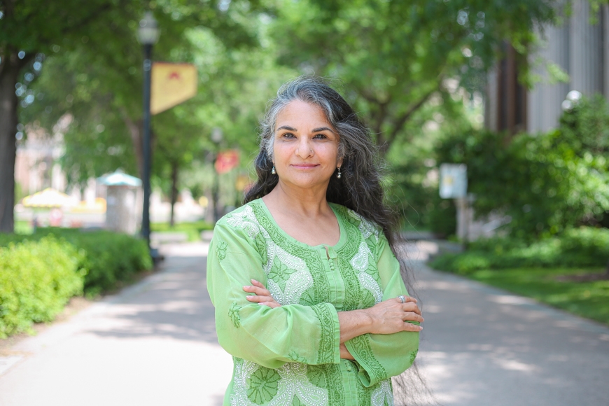 Richa Nagar, a woman with brown skin and gray and black hair, stands outside in the Northrop Mall on a sunny day