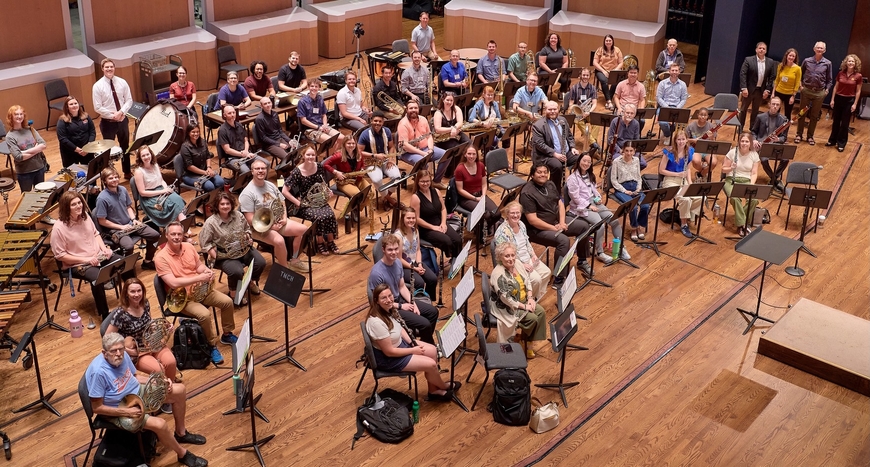 The afternoon workshop band of the Wind Band Conducting Workshop posing for a photo on the Ted Mann Concert Hall Stage