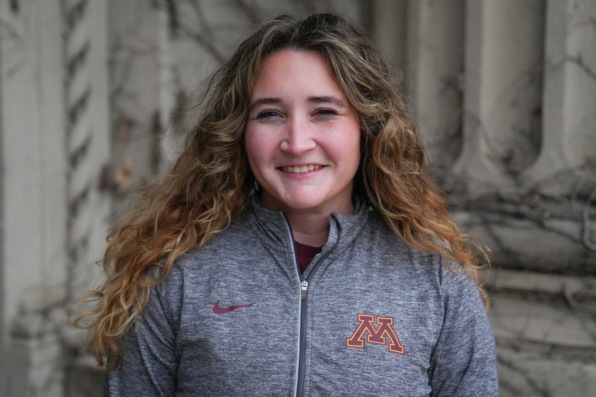 Headshot of Alison Rasso wearing a UMN sweatshirt in front of a campus building
