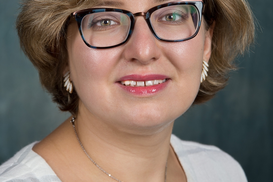 Natalie Belsky, a person with short blond hair and light skin, wearing glasses and jewelry