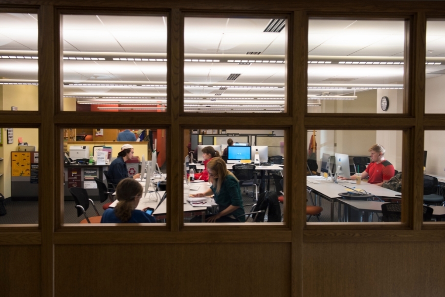 Looking through a window at students studying in the Center for Writing’s computer lab.