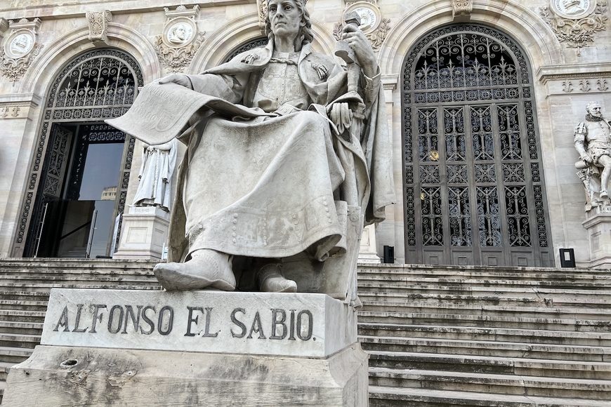 Statue of Alfonso X of Castile, seated with scroll in hand. Outside on steps leading up to Biblioteca Nacional, Madrid. 