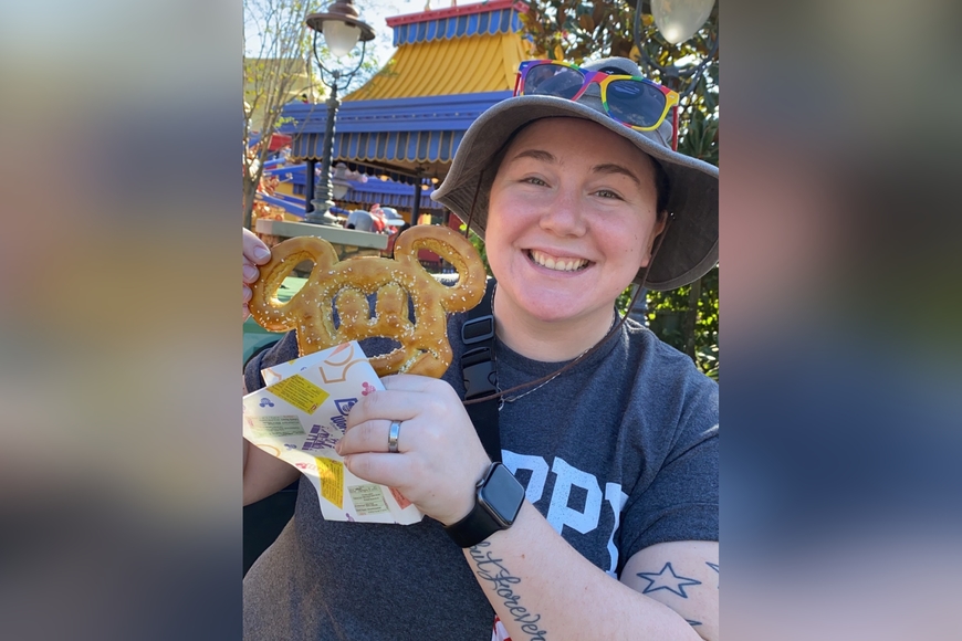 Elizabeth Hockensmith holds a Mickey Mouse-shaped churro and smiles at the camera