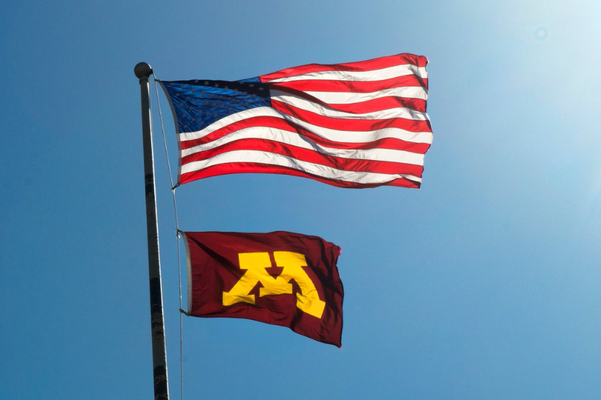 American flag and University of Minnesota flag against a sky blue background