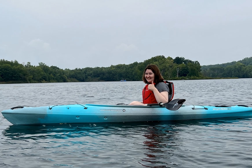 Hannah Ward, a white woman with brown hair, kayaking on a lake