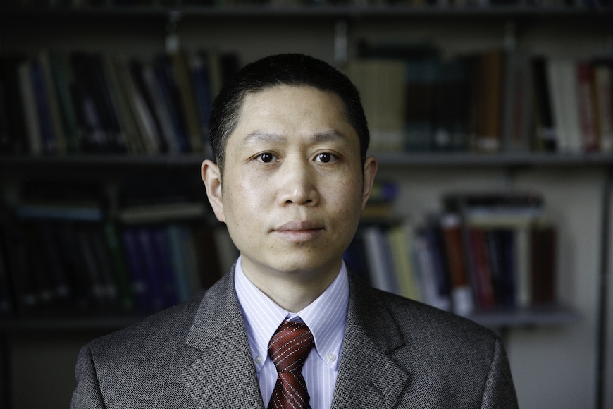Hui Zou, a person with short, black hair, light brown skin, wearing a suit and tie