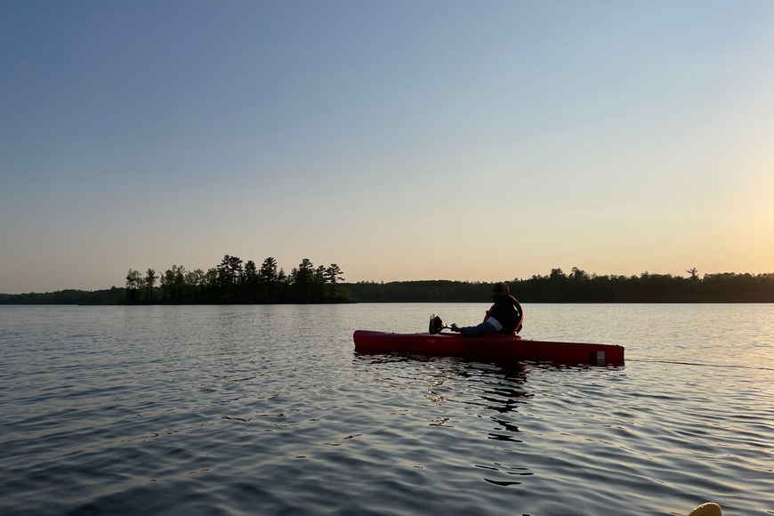 Image of a person on a kayak on Lake Itasca in the evening