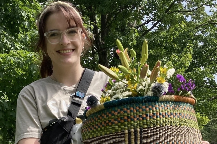 Photo of Julia Knudten outdoors holding a basket of plants