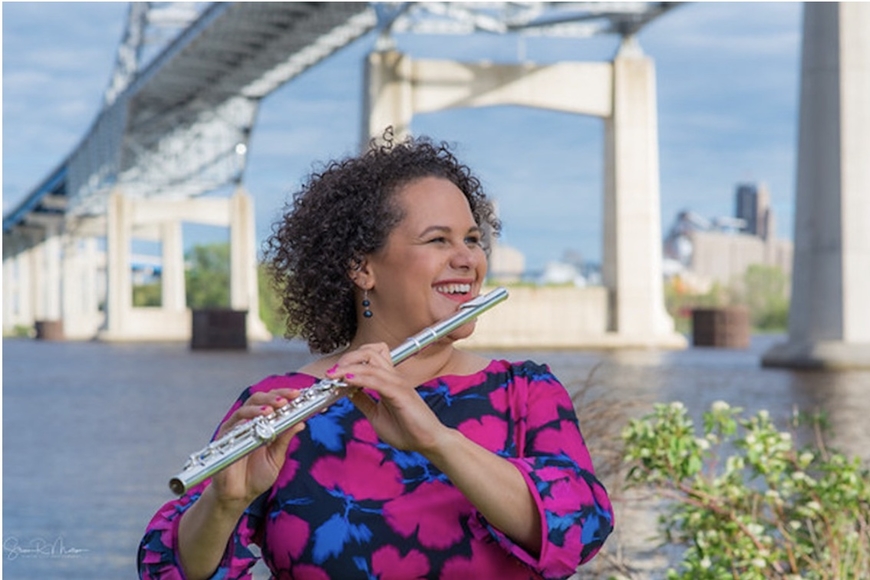 School of Music Alumna Paula Gudmundson poses with her flute in front of a bridge