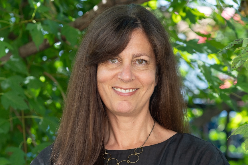 A photo of a person with dark hair wearing a black shirt standing in front of a tree