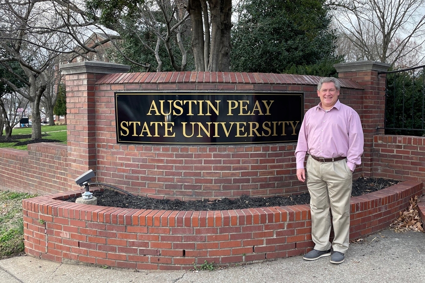 Michael Licari standing next to a sign that says Austin Peavy State University