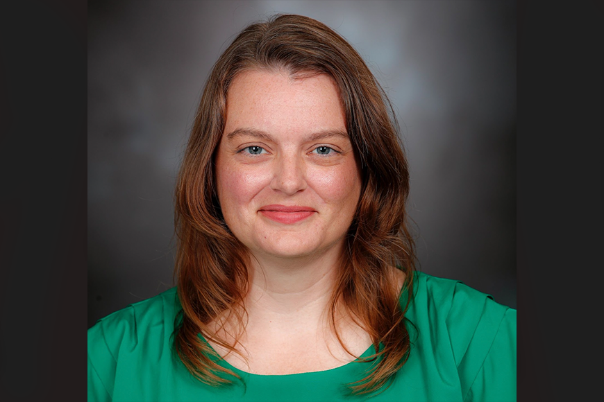 Woman with shoulder length brown hair and green shirt smiling