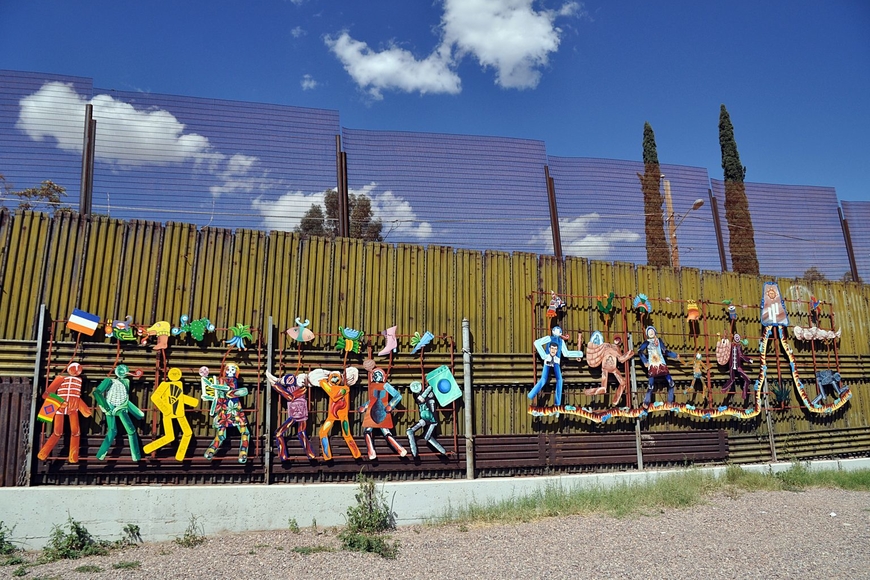 Featured image: Paseo de Humanidad (Parade of Humanity), by Alberto Morackis, Alfred Quiróz, and Guadalupe Serrano. The painted metal artwork is attached to the Mexican side of the US border wall in the city of Heroica Nogales in the Sonoran Desert. Photograph by Jonathan McIntosh / Flickr (CC BY 2.0)