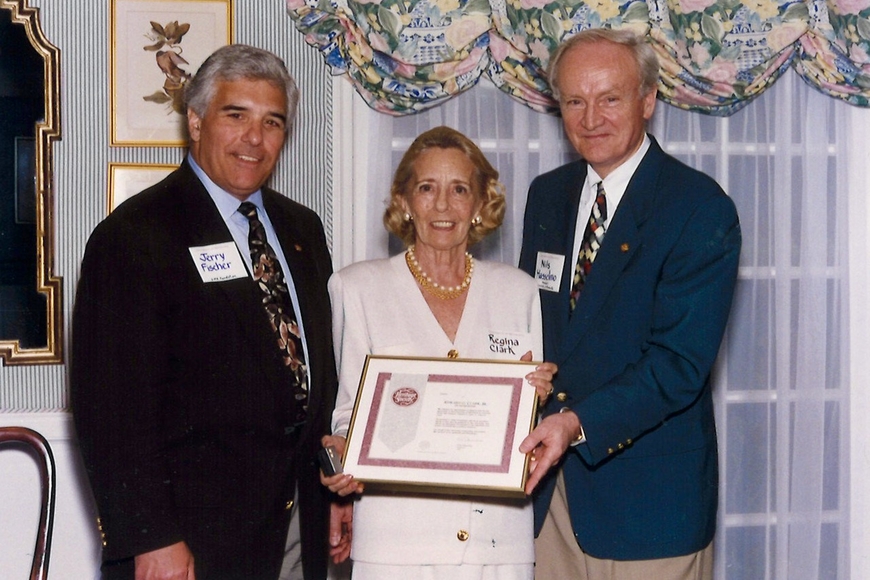 Group of 2 men and 1 woman. The woman is in the center and holds a framed certificate.