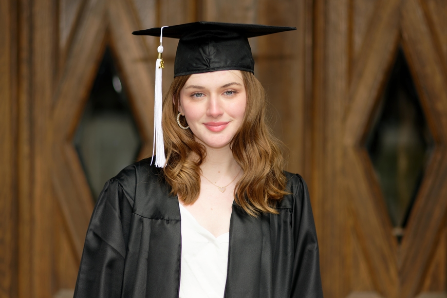 Sabina Berg smiles at the camera wearing a graduation gown and cap