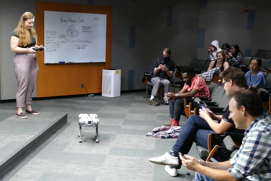 A guest speaker demonstrates the movement of a quadruped robot to interested campers.