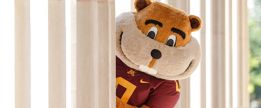 Goldy gopher peaking out from behind column