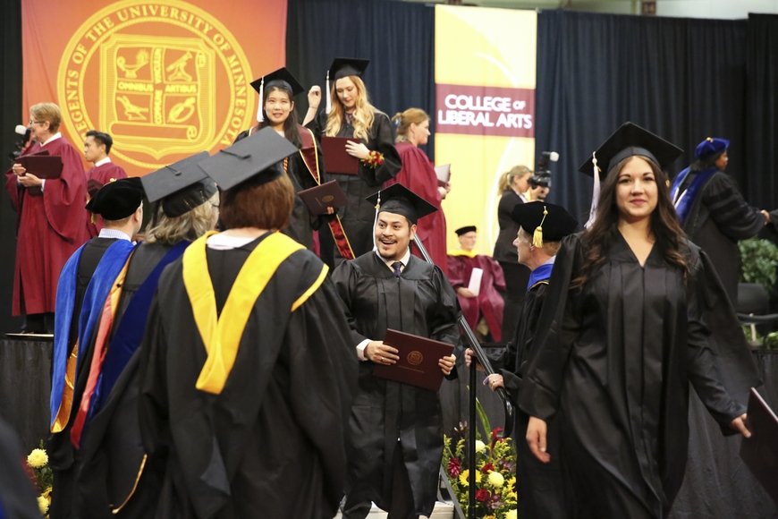 Writing Studies student being congratulated by instructors at 2017 commencement.