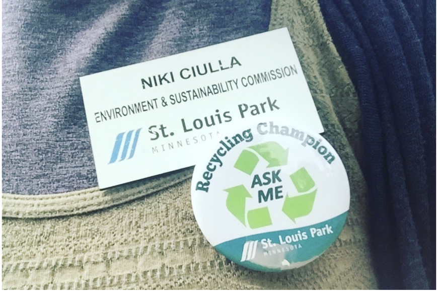 Photo of Niki Ciulla name tag at St. Louis Park Environment & Sustainability Commission, and a button that reads Recycling Champion Ask Me