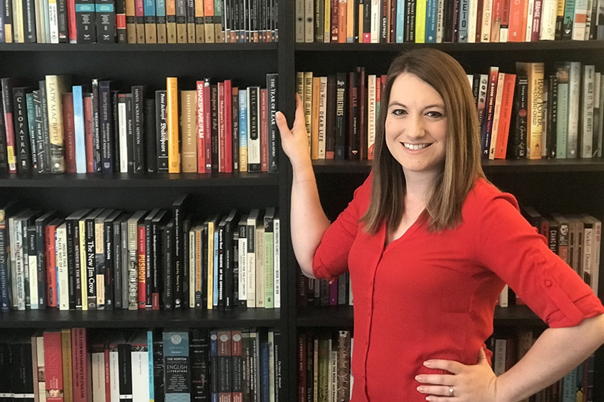 PhD student Jenna Dreier in red dress in front of full book shelves