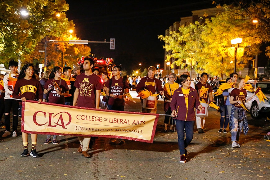 Photo of CLA homecoming parade unit. People wearing maroon and gold and carrying a CLA banner.