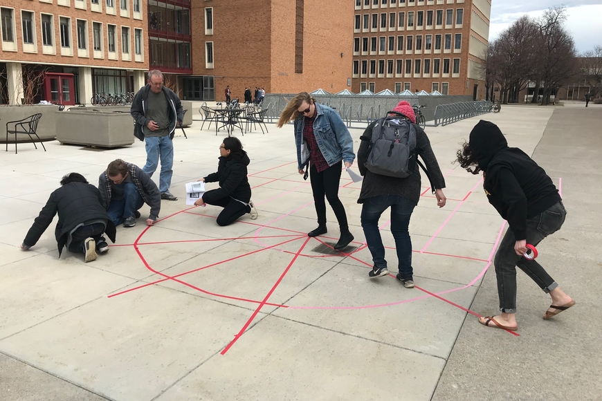 Students in an undergraduate Art History course used colored gaff tape in a courtyard on campus to create a to-scale floor plan of a medieval cathedral.