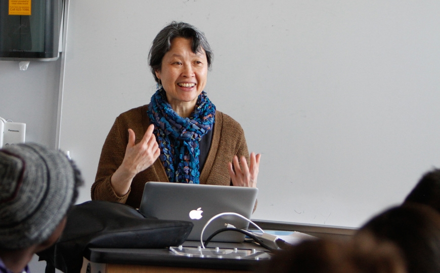 Professor Josephine Lee teaching at podium with white board behind