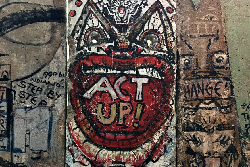 A piece of the Berlin Wall featuring a graffiti mouth that reads Act Up!