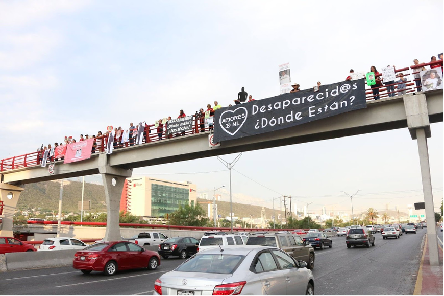 group of people holding a black cloth banner on an overpass
