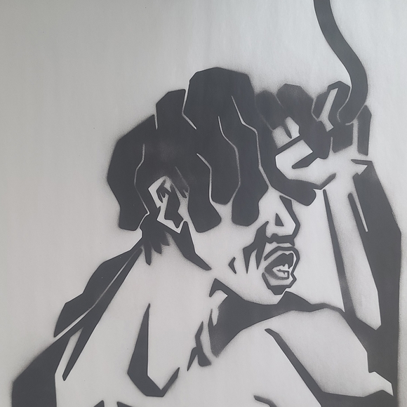 Black and white stencil spray paint image of a person holding a cord against their forehead. 