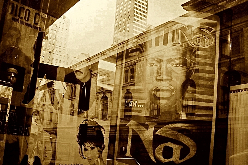 An array of layered photographs featuring an urban cityscape covered with advertisements including the 1999 “I am Nas” album cover featuring the Black musician wearing prosthetics and makeup to mimic the mask of Tutankhamun.
