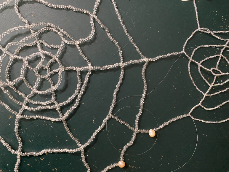 Closely cropped view of a spider web like object made out of glass beads.
