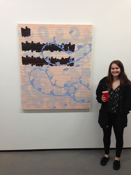 Person with solo cup stands next to a large abstract painting